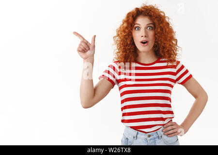 Alcun modo wow hai sentito. Impressionato affascinato bella redhead elegante ragazza mascella caduta affannosa divertito sorridono felici occhi entusiasti pointin Foto Stock