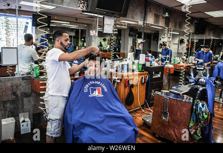 Gli uomini di ottenere i loro capelli tagliati e in stile a una piccola azienda Barber shop in Kensington Philadelphia Foto Stock