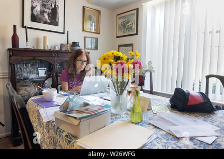 A 63 anni donna ebrea si siede al suo tavolo da pranzo in cui corre la sua piccola attività come fotografo freelance nei sobborghi di Philadelphia Foto Stock