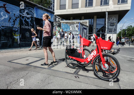 Noleggio bici elettriche da Uber a lato est del muro di Berlino in Germania turisti Foto Stock