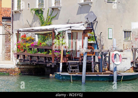 Casa su fondamenta S Angelo, l'isola della Giudecca, con una terrazza in legno sporgente oltre il canale coperto in una massa di colorati per le piante in vaso Foto Stock