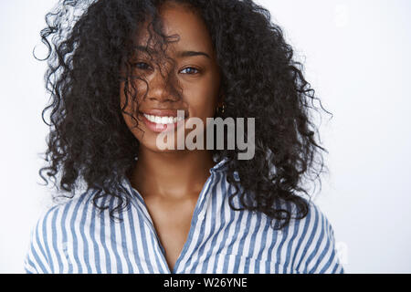 Close-up di spensierata positivo happy good-looking sorridente afro-americano donna fashioable giocando ricci acconciatura afro grinning felicemente esprimendo positiv Foto Stock