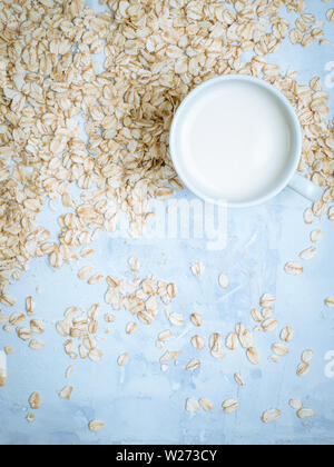 Avena drink latte nella tazza bianca e di fiocchi di cereali sul banco di cucina. Lay piatto. Copia dello spazio. Foto Stock