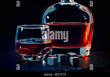 Bar ancora in vita con il whisky e il nero shungite cubetti di refrigerazione o riutilizzabili blocchi di ghiaccio contro uno sfondo scuro concettuale del un night club o la vita notturna Foto Stock