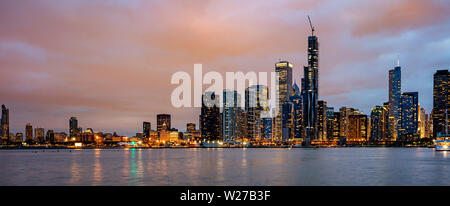 Sullo skyline di Chicago panorama, l'orario del tramonto. Vista panoramica della città di Chicago waterfront grattacieli illuminati, cielo molto nuvoloso in serata Foto Stock