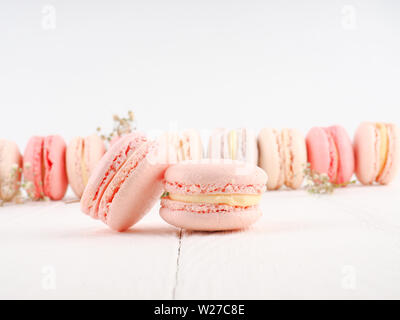 Colorato in francese o in italiano macarons stack su bianco tavola di legno con copia spazio per lo sfondo. Per dessert serviti con il tè del pomeriggio o un coffee break. Foto Stock