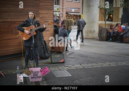 London, Regno Unito - Aprile, 2019. Una femmina giovane musicista di strada di eseguire nel mercato di Borough, uno dei più famosi del mercato alimentare a Londra. Foto Stock