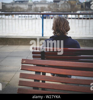 Vista di un uomo solitario seduta su una panchina da dietro. Formato quadrato. Foto Stock