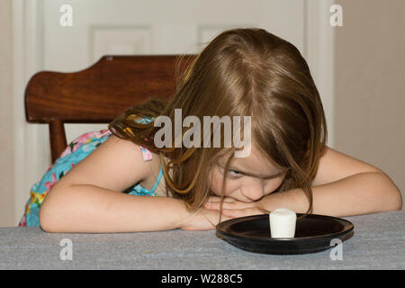 Un giovane bambino seduti ad un tavolo aspettando pazientemente per un marshmallow Foto Stock