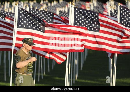 West Dundee, Illinois, Stati Uniti d'America. 06 Luglio, 2019. Veterano del Vietnam ROBERT KREBIEHL di Carpetersville, Illinois passeggiate da una bandiera americana visualizzati in corrispondenza della parete che guarisce, 375 piedi lungo e 7,5 piede alta replica del Vietnam Veterans Memorial a Washington, DC la mostra itinerante onora gli oltre 3 milioni di americani che hanno servito nei militari durante la guerra e riporta i nomi dei più di 58,000 persone che sono state uccise. Credito: H. Rick Bamman/ZUMA filo/Alamy Live News Foto Stock