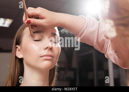 Trucco artisti applicare un primer sul ciglio di una donna Foto Stock