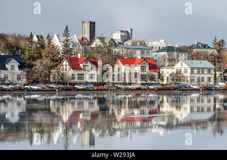 Reykjavik, Islanda, febbraio 23, 2019: le tradizionali case di legno e acciaio ondulato, nonché Landakotskirkja chiesa riflettere nel ghiaccio su Foto Stock