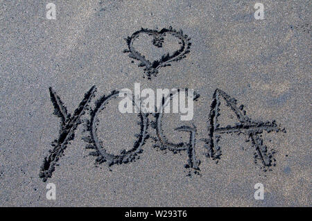 Lo Yoga iscrizione disegnati su una miscela di nero e marrone sabbia in Canggu, Bali - Indonesia Foto Stock