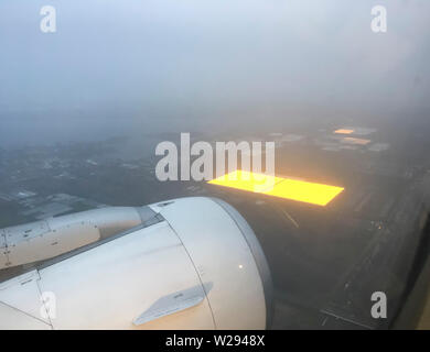 Schiphol, Paesi Bassi - 21 dicembre 2018: fotografia aerea di un grandi serre agricole nei Paesi Bassi che sono illuminati internamente per una migliore crescita dei prodotti di fattoria durante l'inverno. Foto scattata da un atterraggio gli aeromobili in avvicinamento dall'aeroporto Schiphol di Amsterdam al mattino presto. Foto Stock