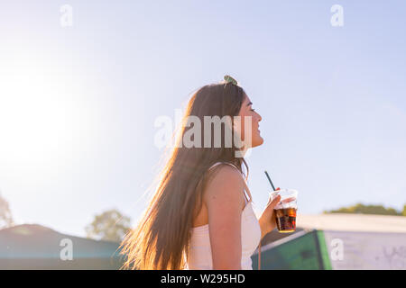 Ragazza godendo il momento in un festival con un drink in una giornata di sole a Monaco di Baviera Foto Stock