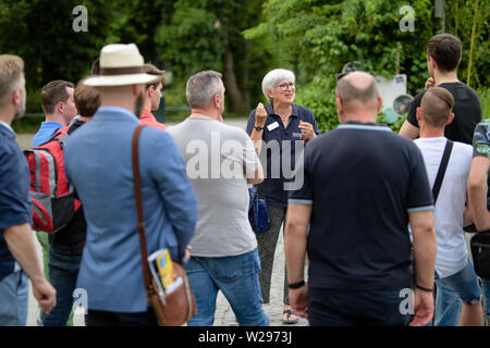 Monaco di Baviera, Germania. 06 Luglio, 2019. Ilse singhiozzi (M), biologo e guida dello zoo, parla con il suo gruppo durante il suo tour guidato sul comportamento omosessuale negli animali a Zoo di Hellabrunn. In occasione della Settimana di orgoglio e Christopher Street Day a Monaco di Baviera, lo zoo è che offre questo speciale tour guidato per la prima volta in diverse serate. (A dpa 'dove l' omosessualità è un vantaggio: zoo tour about gay animali") Credito: Matthias esitano di fronte/dpa/Alamy Live News Foto Stock