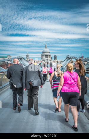 Due uomini di mezza età in abiti grigi che camminano attraverso il Millennium Bridge (Blade of Light), Londra, Regno Unito Foto Stock