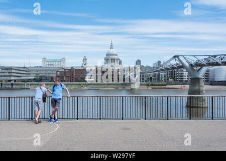 Due uomini in chat di fronte alla Tate Modern, si affaccia la Cattedrale di St Paul, Londra, Regno Unito Foto Stock