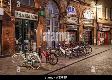 Le biciclette parcheggiate lungo una bella strada storica di Tolosa (Francia) a notte Foto Stock