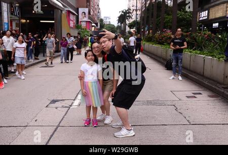 Hong Kong, Cina. 7 Luglio, 2019. A Hong Kong famiglia prende un selfie sul medio di Nathan Road dopo il viale principale è stato bloccato durante il rally di massa di questo pomeriggio.Migliaia di cittadini ha organizzato un raduno di massa sul lato di Kowloon oggi chiedono il ritiro completo della legge in materia di estradizione.Luglio-7, 2019 Hong Kong.ZUMA/Liau Chung-ren Credito: Liau Chung-ren/ZUMA filo/Alamy Live News Foto Stock