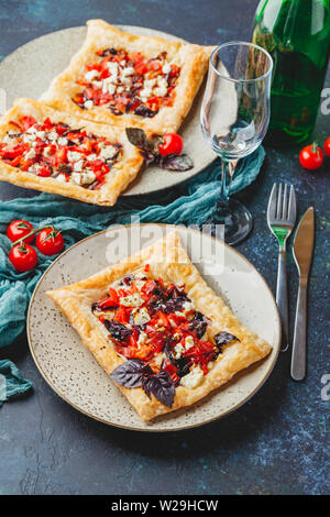 Pasta sfoglia canapes con pomodori, dolci peperoni, salame, formaggio feta e basilico viola. Foto Stock