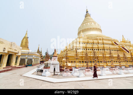 Bagan, Myanmar - Marzo 2019: monaco buddista camminare al fianco di Shwezigon Paya tempio dorato. Foto Stock