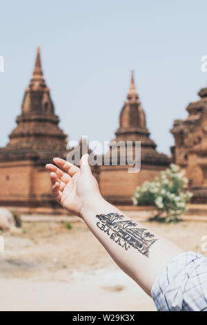 Bagan, Myanmar - Marzo 2019: a mano con un tatuaggio che mostra i templi e pagode di antica Bagan sullo sfondo Foto Stock