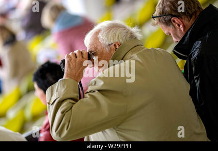 Amburgo, Germania. 07 Luglio, 2019. Corse di cavalli: galoppo, Derby Settimana di Amburgo. Un visitatore di Derby settimana segue una gara con un binocolo. Credito: Axel Heimken/dpa/Alamy Live News Foto Stock