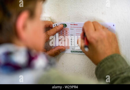 Amburgo, Germania. 07 Luglio, 2019. Corse di cavalli: galoppo, Derby Settimana di Amburgo. Un visitatore di Derby settimana compila un talloncino scommesse. Credito: Axel Heimken/dpa/Alamy Live News Foto Stock