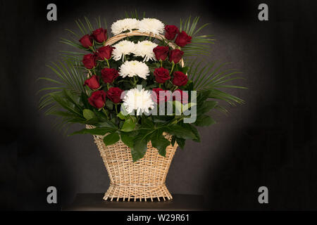 Rituale cesto funebre con Fiori su fondo nero.floreale di fiori nel cesto viene utilizzato per i funerali e segnalibri. Mourni Foto Stock