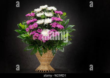 Rituale cesto funebre con Fiori su fondo nero.floreale di fiori nel cesto viene utilizzato per i funerali e segnalibri. Mourni Foto Stock