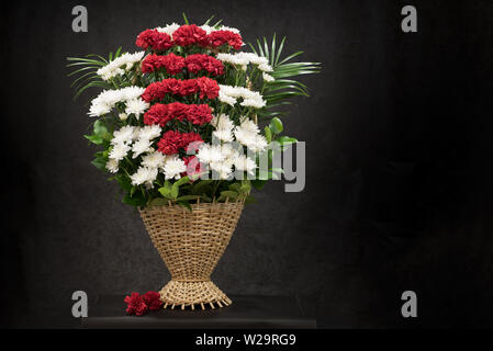 Rituale cesto funebre con Fiori su fondo nero.floreale di fiori nel cesto viene utilizzato per i funerali e segnalibri. Mourni Foto Stock