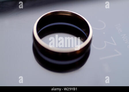 Il impegnato un anello di fidanzamento si siede in cima a un cellulare di visualizzazione di data e ora. Foto Stock