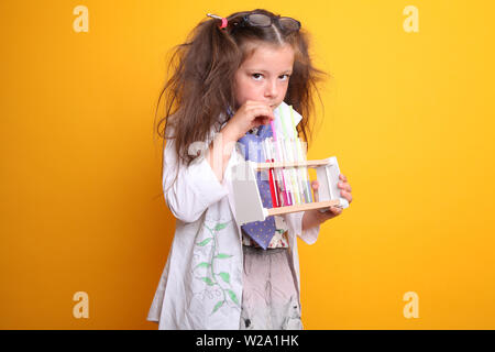 Signor - Scienza Geek giovane ragazza / femmina - 7 anni - bambino bere da provette con paglia a fotocamera su sfondo giallo Foto Stock