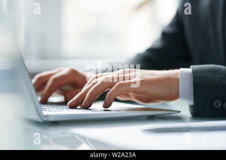 Le mani del mobile contemporaneo broker premendo i tasti della tastiera del notebook Foto Stock