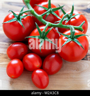 Vive e i pomodori ciliegia sulla superficie di legno Foto Stock