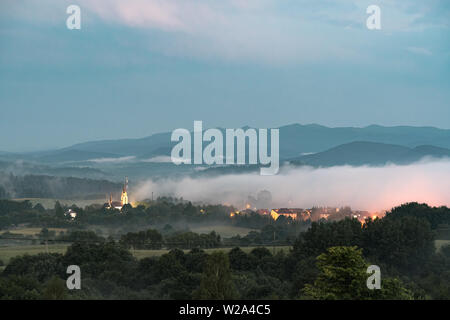 La nebbia che scendono dalla gamma della montagna di villaggio al tramonto. Paesaggio colpo di Lutowiska nei monti Bieszczady, Polonia. Foto Stock