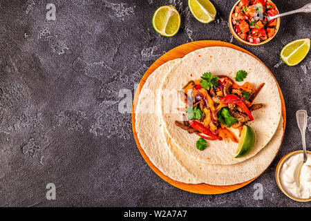 Le FAJITAS colorato con pepe e cipolle, servita con tortillas, salsa e panna acida. Foto Stock