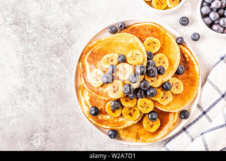 Frittelle di banane, mirtilli sulla piastra bianca, il fuoco selettivo. Foto Stock