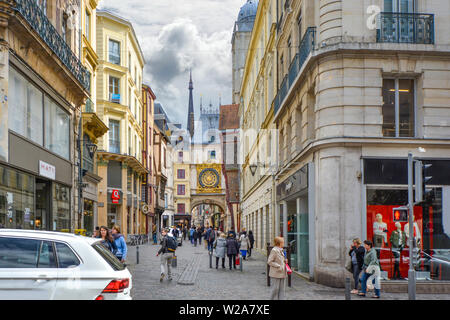 I turisti e i locali di passeggiata la Rue du Gros Horloge con il famoso orologio astronomico in background su un nuvoloso giorno a rouen Francia Foto Stock