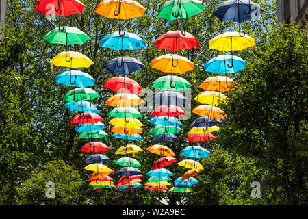 Allegro, display a colori delle colorate ombrelloni su una strada di Liverpool, Regno Unito Foto Stock