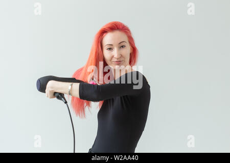 Parrucchiere stilista e concetto di persone - una giovane donna la sua asciugatura Capelli rossi su sfondo bianco con spazio di copia Foto Stock