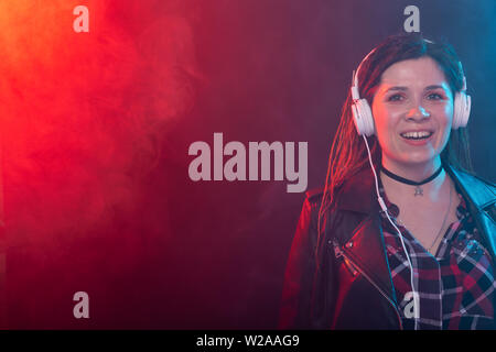 Godetevi, meloman e concetto di persone - una giovane donna con dreadlocks ascoltando la musica, ritratto su sfondo scuro con spazio di copia Foto Stock