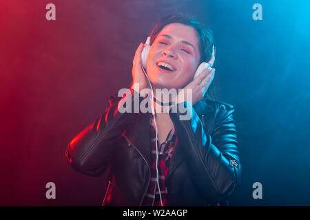 Godetevi, meloman e concetto di persone - una giovane donna con dreadlocks ascoltando la musica, ritratto su sfondo scuro Foto Stock