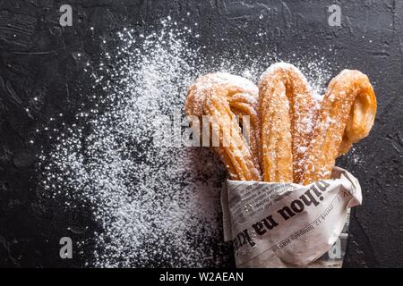 Churros bastoni caldo fresco nel sacchetto di carta sul buio Foto Stock