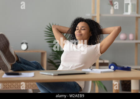 Felice ragazza africana studente rilassante studio finito seduti alla scrivania Foto Stock
