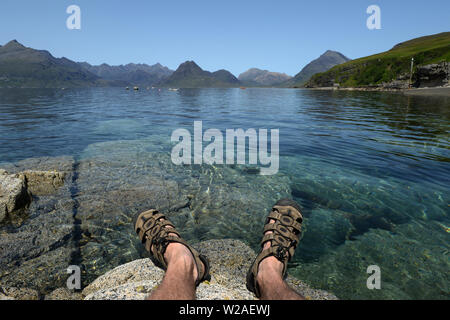 Vista da Elgol sopra Loch Skavaig al Cuillin Hills con piedi appesi sopra acqua chiara Foto Stock