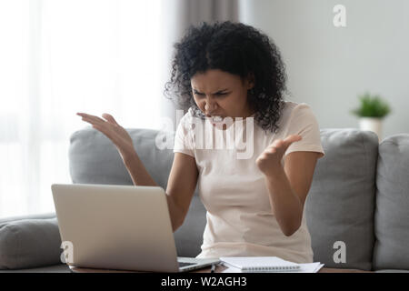 Arrabbiato ha sottolineato giovane nero donna che guarda la sensazione di laptop infastiditi Foto Stock