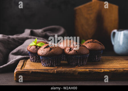 Gruppo di muffin al cioccolato sulla tavola di legno, sfondo nero. Tonica immagine. gustosi piatti fatti in casa Torte al cioccolato Foto Stock