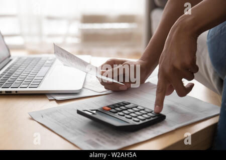 Donna africana azienda fatture su supporto cartaceo utilizzando la calcolatrice, vista ravvicinata Foto Stock